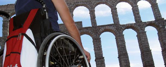 Immagine di persona in carrozzina di fronte a un edificio storico poco accessibile. Bisogna garantire accessibilità a tutti